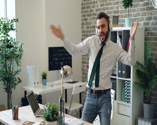 Man stretching arms upwards in modern office workspace