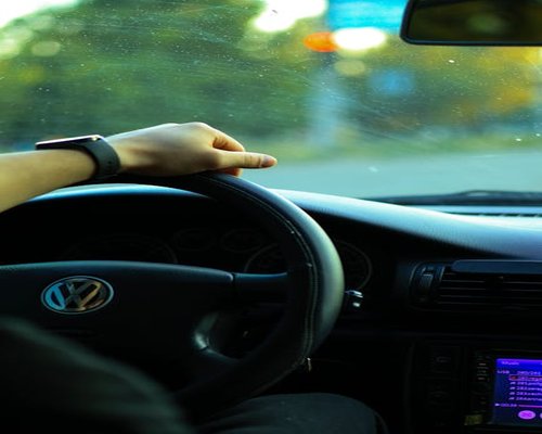 Close up of hands gently gripping steering wheel in traffic